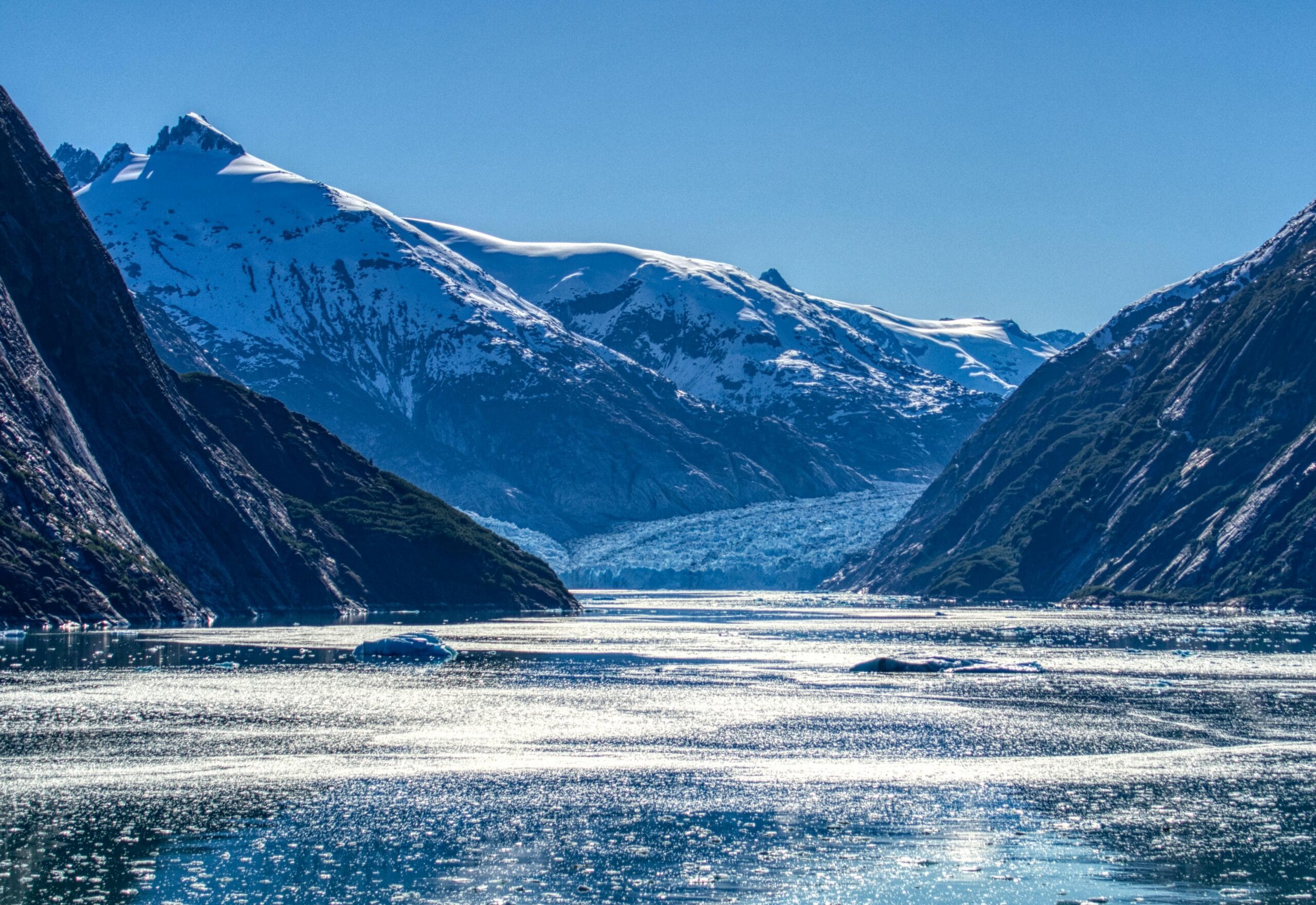 A stunning view of snowcapped mountains and a glistening fjord in Alaska's tranquil wilderness.