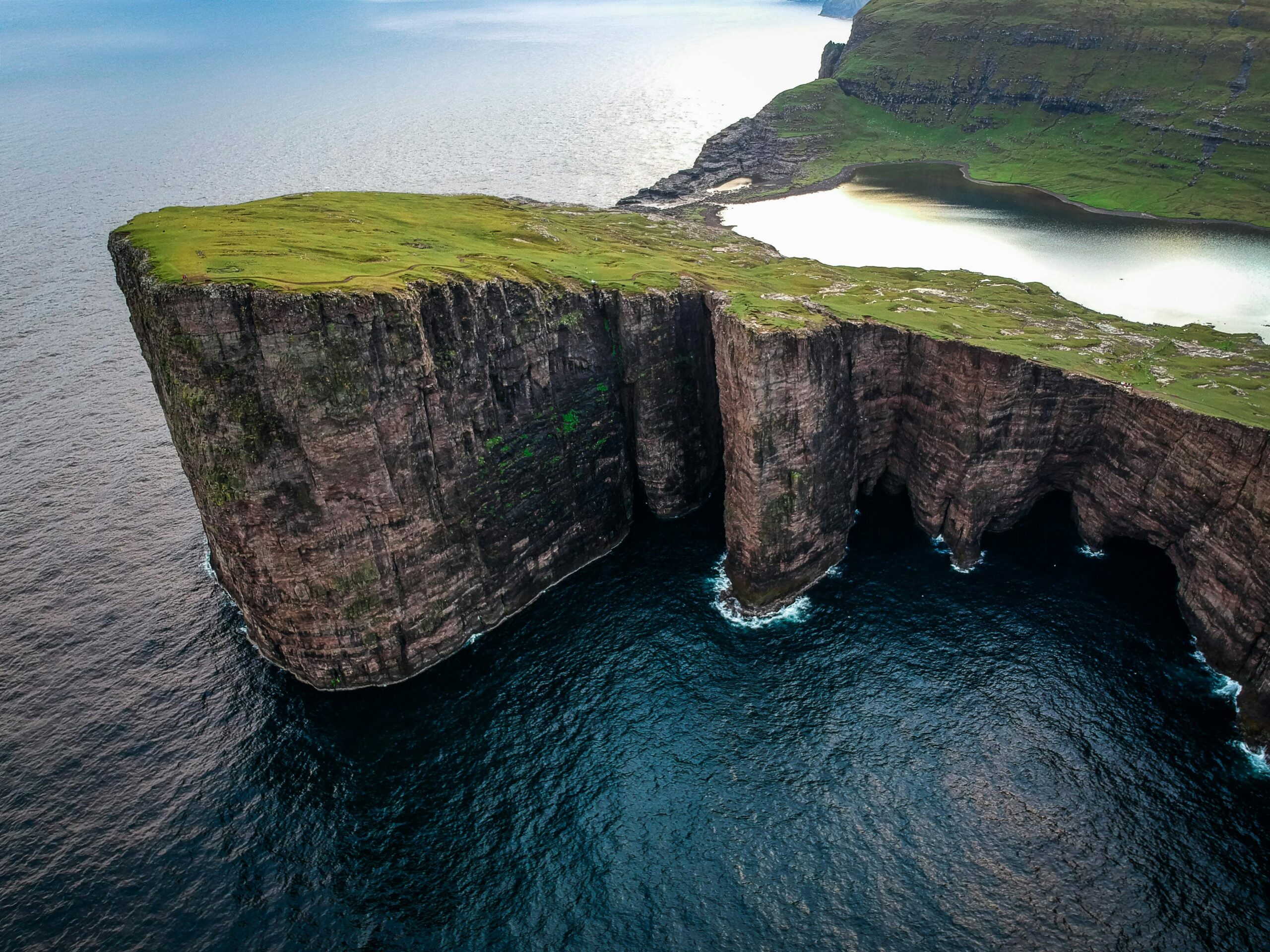 A breathtaking aerial shot of the dramatic cliffs of Sørvágsvatn against the ocean in Faroe Islands.