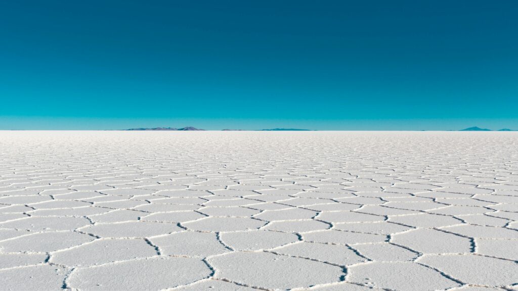 Top 9 Awe-Inspiring Destinations You Won't Believe Are Real Vast salar with geometric patterns under a clear blue sky in Bolivia's Uyuni.