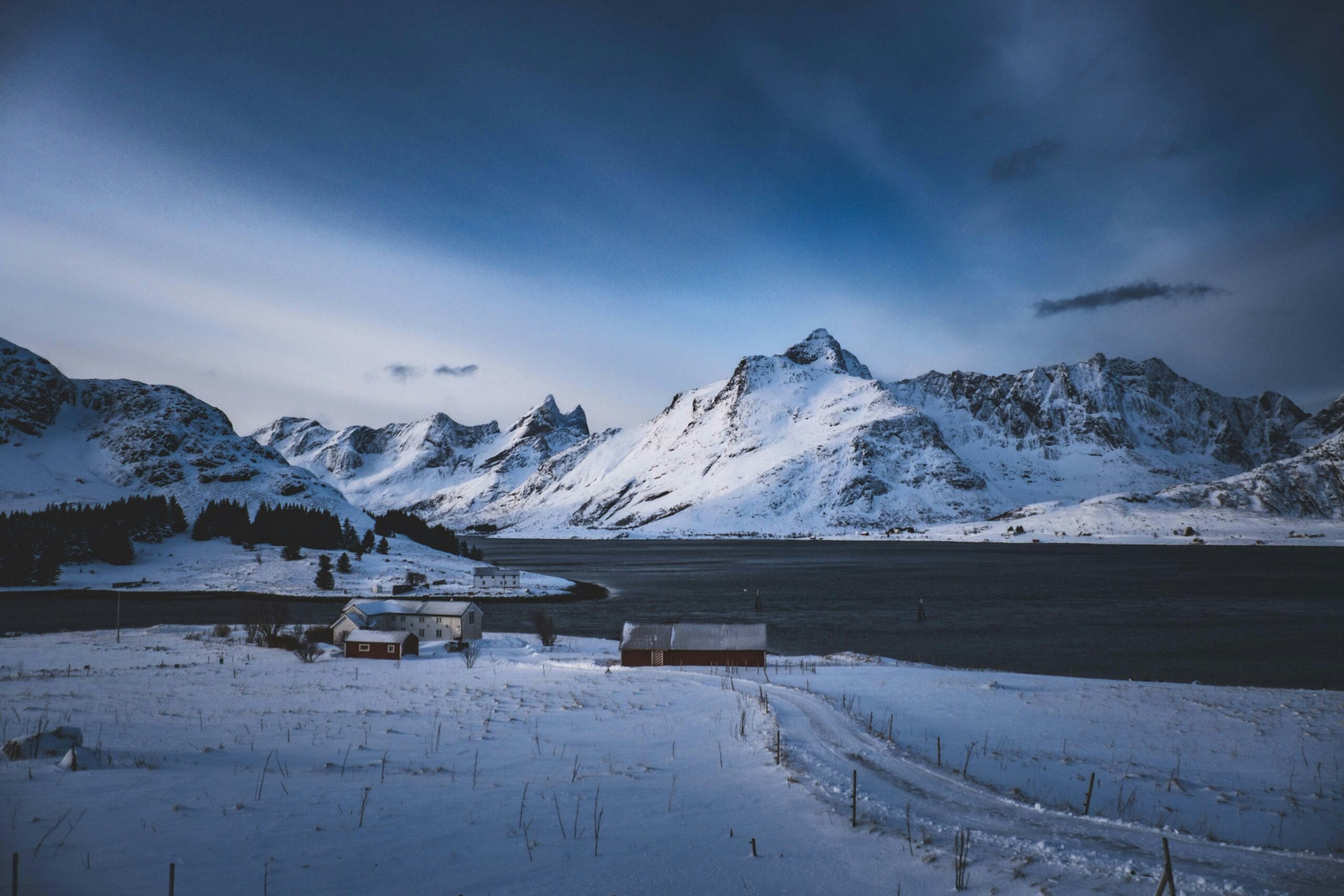 Tranquil snowy mountains in Lofoten, Norway with a rustic cabin at dusk.