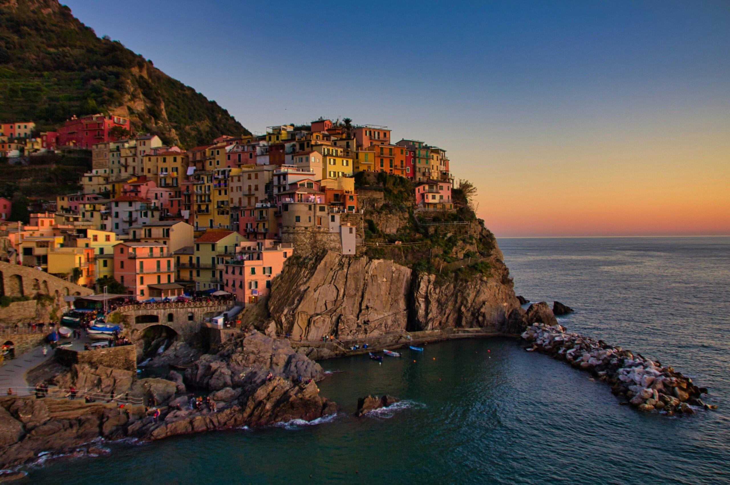 Golden hour view of Manarola, Cinque Terre with colorful houses and calm sea.