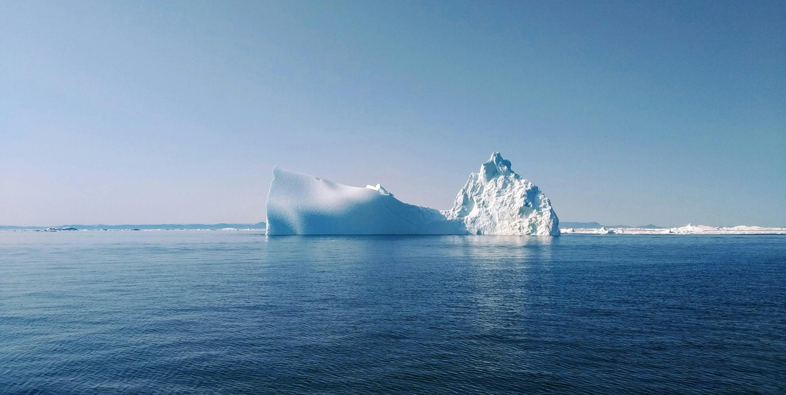 Stunning iceberg floating in the ocean near Ilulissat, Greenland under a clear blue sky.